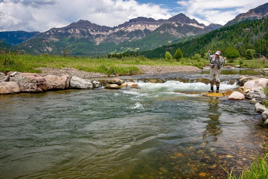 Angler fly fishing in mountain river Angler fly fishing in mountain river