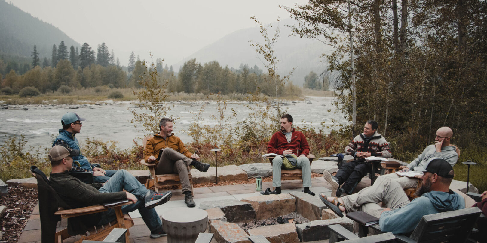 Friends gathered around fire pit by river Friends gathered around fire pit by river