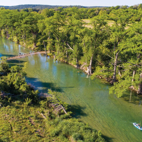 Aerial view of small boat on tree-lined river Aerial view of small boat on tree-lined river